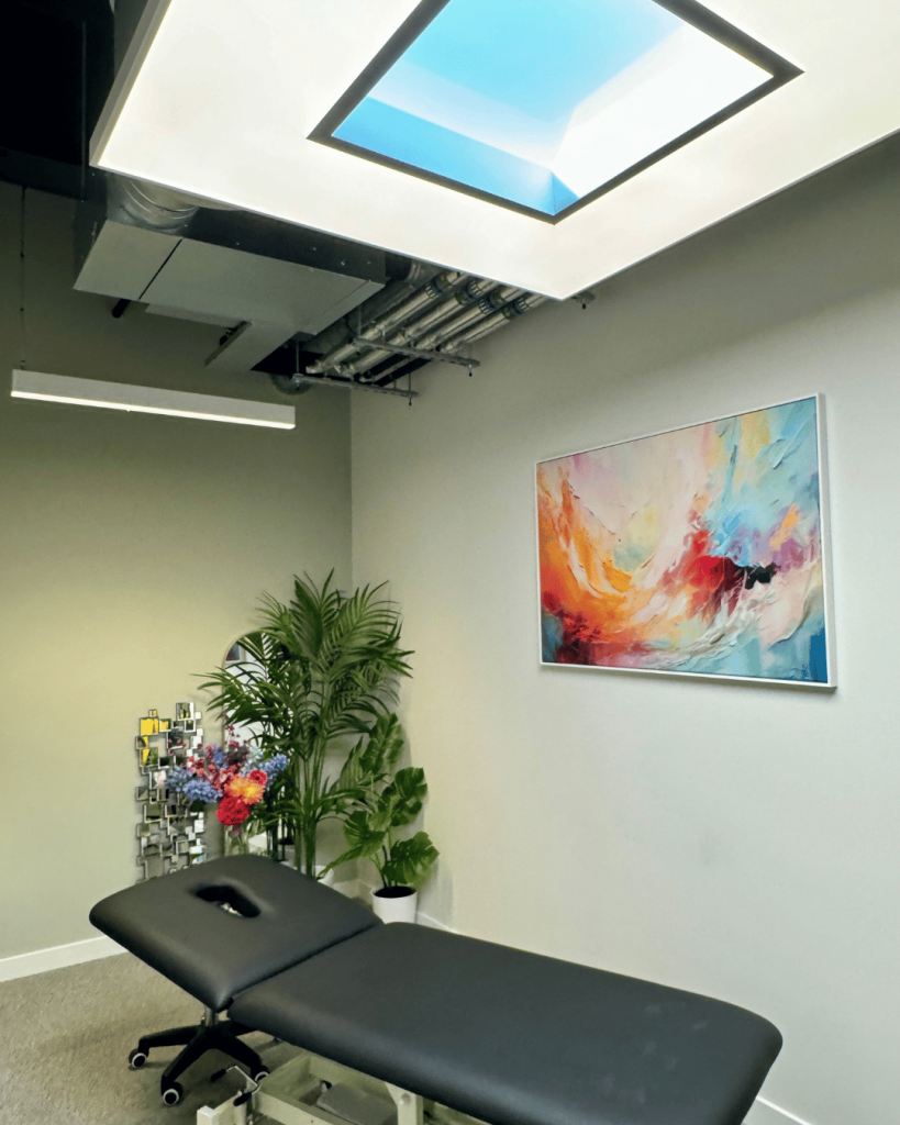 Top Fulham Chiropractor's beautiful modern clinic room inside Battersea Power Station, stunning artwork on the walls and lots of plant's and flowers for a modern fresh look.