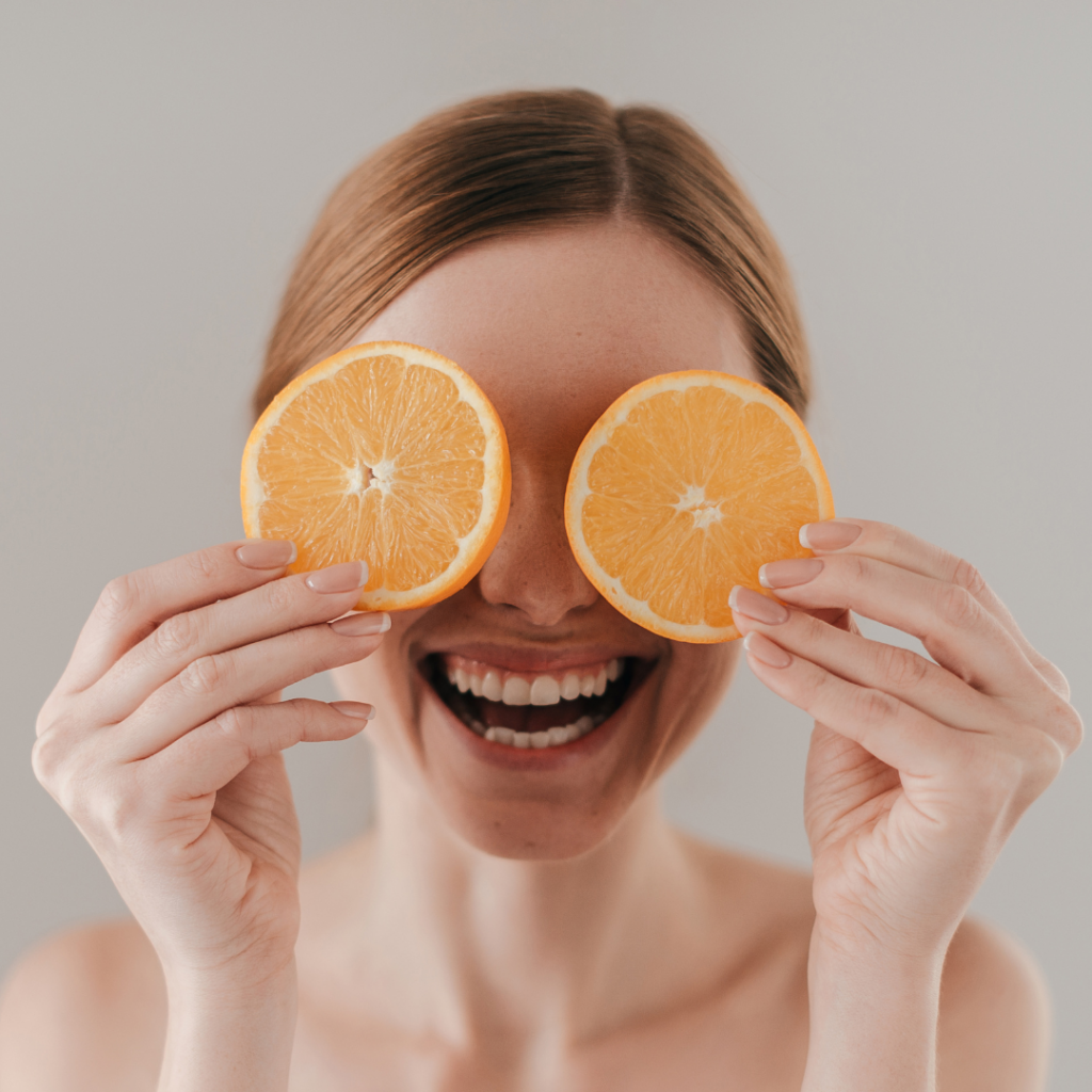 Happy woman smiling with oranges in her hands after seeing Top London Chiropractor a Chiropractor in Pimlico at Battersea and Chelsea