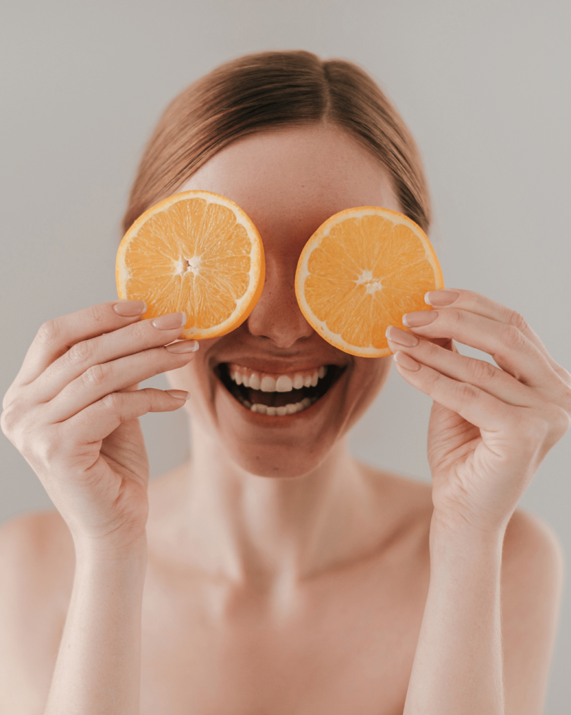 Happy woman smiling with oranges in her hands after seeing Top London Chiropractor a Chiropractor in Clapham at Battersea and Chelsea